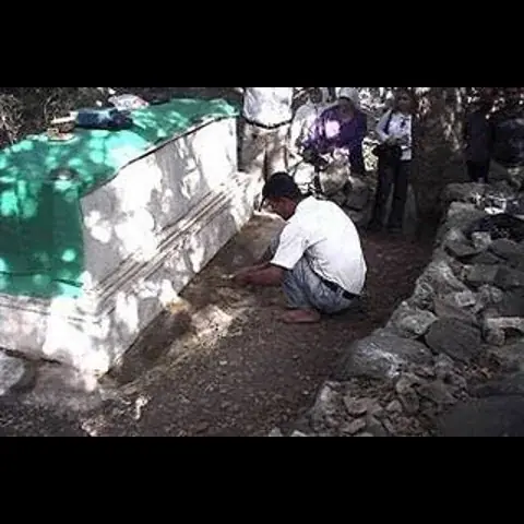 crowd around Ayamn's grave  filling vessels of water coming from grave as a kind of blessing